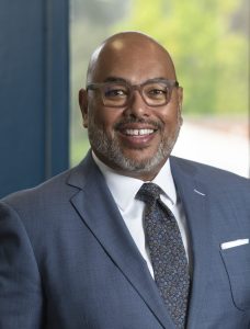 Vice Chancellor Banks stands in his office wearing a suit with his hands in his pockets, looking at the camera