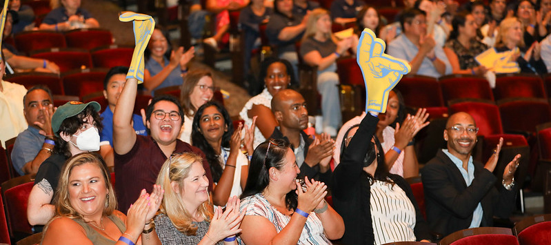 Employees cheering and clapping while seated inside the Barclay theatre.